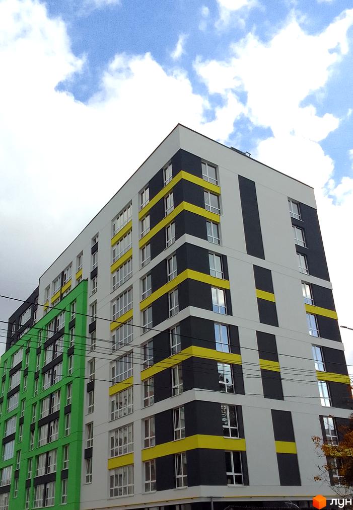 Зовнішній вигляд новобудови на вул. Заміська, 16, з яскравим фасадом та великою кількістю вікон. Будинок має багатоповерхову структуру з чергуванням кольорових секцій.