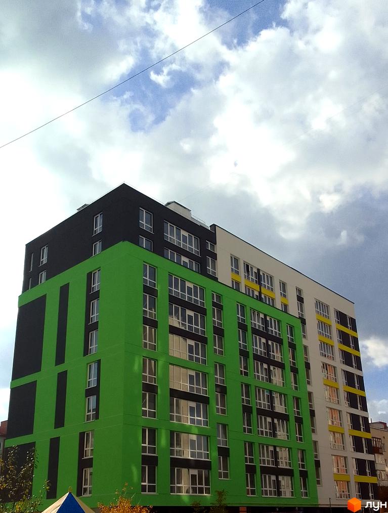 Зовнішній вигляд новобудови на вул. Заміська, 16, з яскравим зеленим та чорним фасадом, що контрастує з хмарним небом.