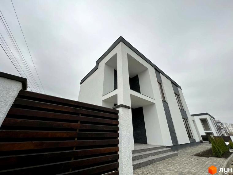 Котеджне містечко Перлина Процева: фасади будинків з білою штукатуркою та темною цеглою, вимощені доріжки та зелені насадження.