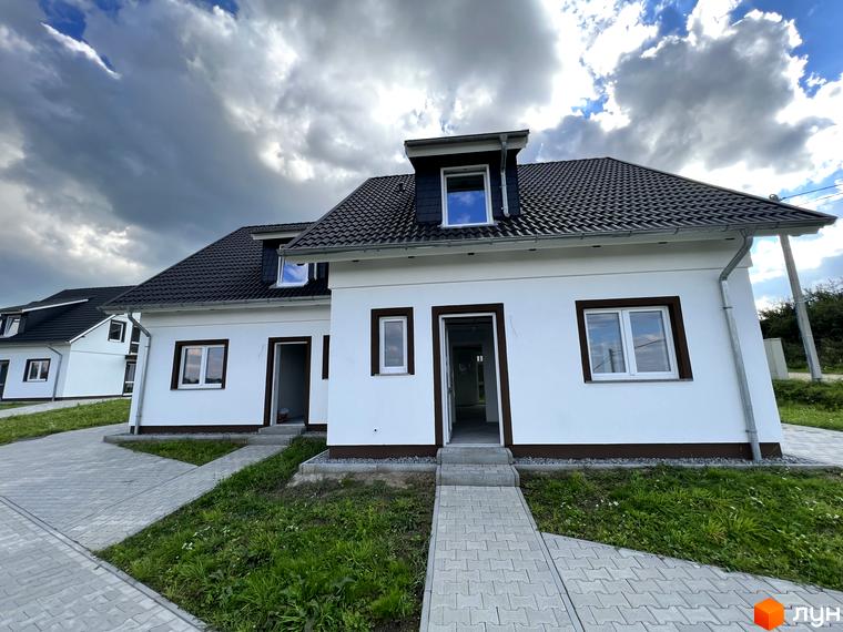 Зовнішній вигляд білих котеджів з темним дахом у котеджному містечку КМ MEINDORF. Навколо будівель розташовані доріжки з плитки та зелена трава.