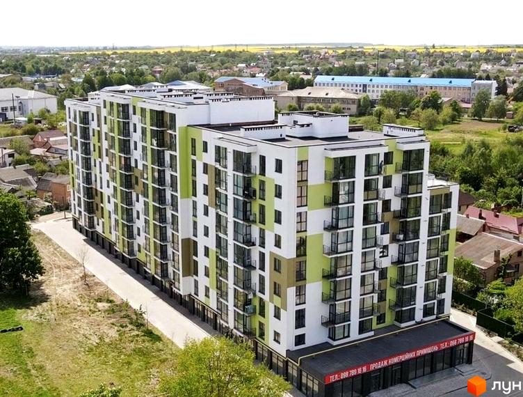 Зображення фасаду Житлового комплексу Затишний Двір-2, багатоповерховий будинок з великими вікнами та балконами. Навколо будинку зелена територія та інші будівлі.