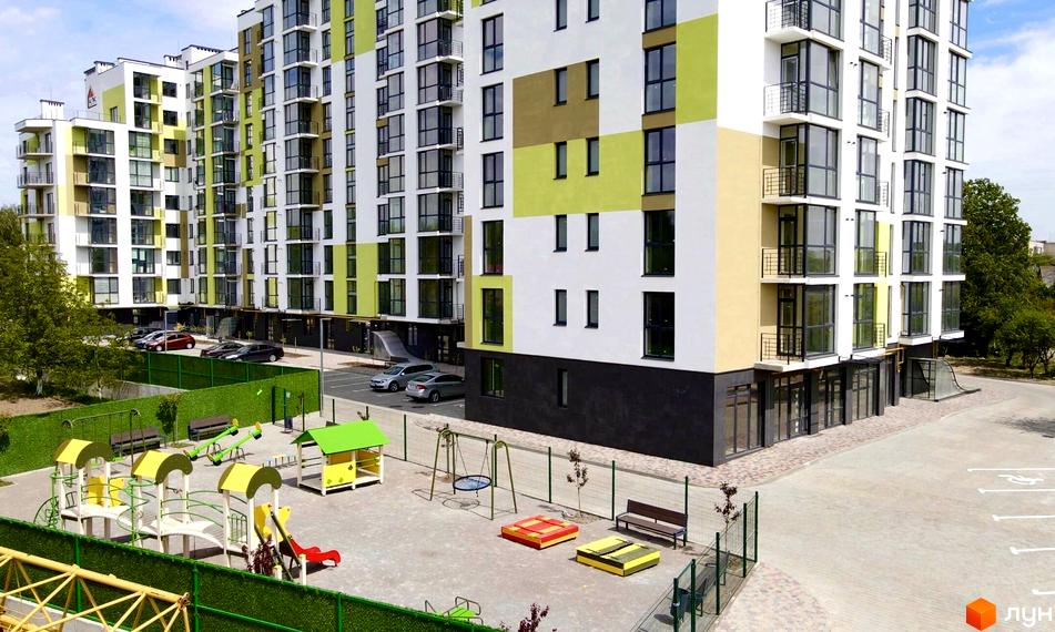 Вигляд багатоповерхового будинку в Житловому комплексі Затишний Двір-2 з дитячим майданчиком та парковкою.