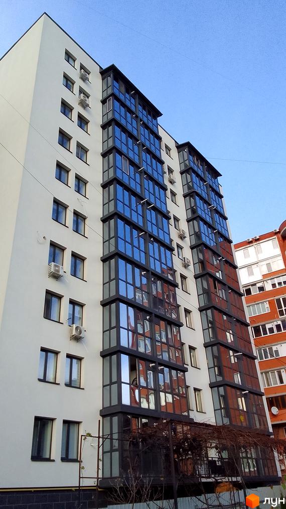 Фасад новобудови на вул. Данила Нечая, 6, з панорамними вікнами та кондиціонерами. Перед будинком видно огорожу та гілки дерев.