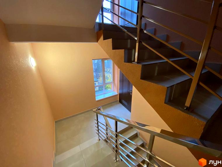 Інтер'єр сходового майданчика в Житловому комплексі Central Avenue з металевими перилами та великим вікном.
