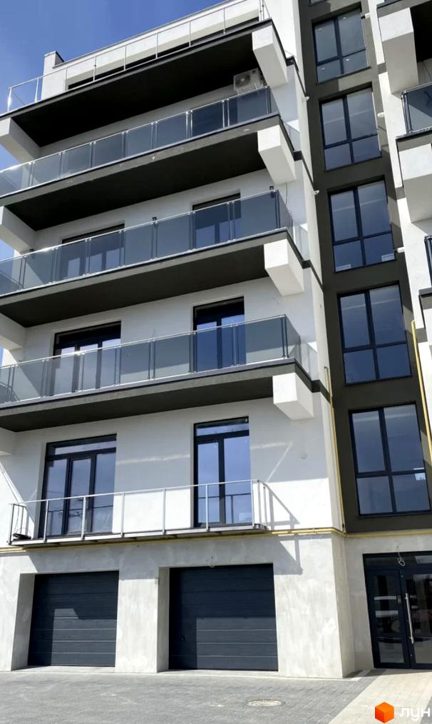 Зовнішній вигляд новобудови ЖК Беладжіо з балконами та великими вікнами. На першому поверсі розташовані гаражні ворота.