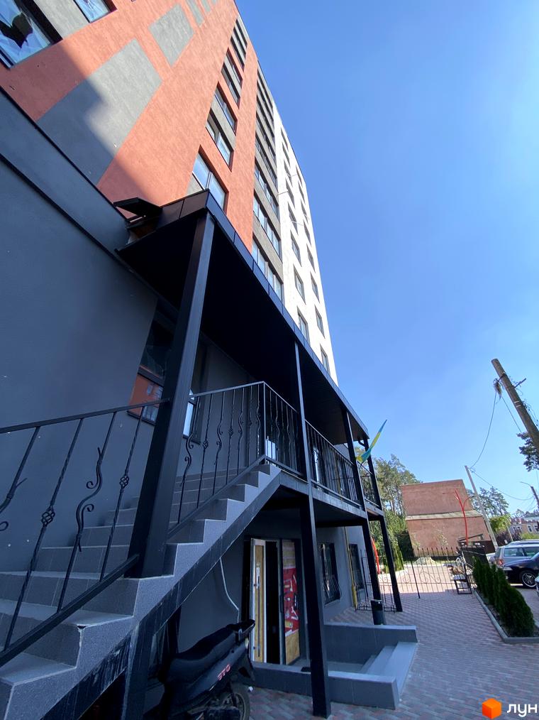 Зовнішній вигляд багатоповерхового будинку ЖК Green Life-3 з цегляним фасадом та балконами. Прибудинкова територія з бруківкою та зеленими насадженнями.