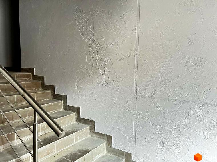 Сходи в новобудові ЖК Сімейний COMFORT з текстурованими стінами та металевим поручнем. Оздоблення стін підкреслює сучасний дизайн інтер'єру.