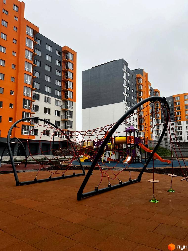 Житловий комплекс Сімейний COMFORT з яскравою фасадною обробкою та дитячим майданчиком з гірками та мотузковим атракціоном. Сучасна новобудова для комфортного життя.