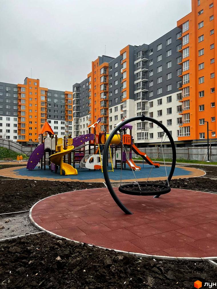 Житловий комплекс Сімейний COMFORT з яскравими фасадами та дитячим майданчиком. Новобудова з оранжевими та сірими секціями, облаштована зонами для відпочинку.