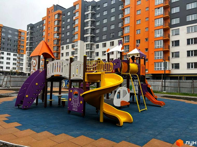 Житловий комплекс Сімейний COMFORT з яскравим дитячим майданчиком. Сучасні будинки з помаранчевими та сірими фасадами.