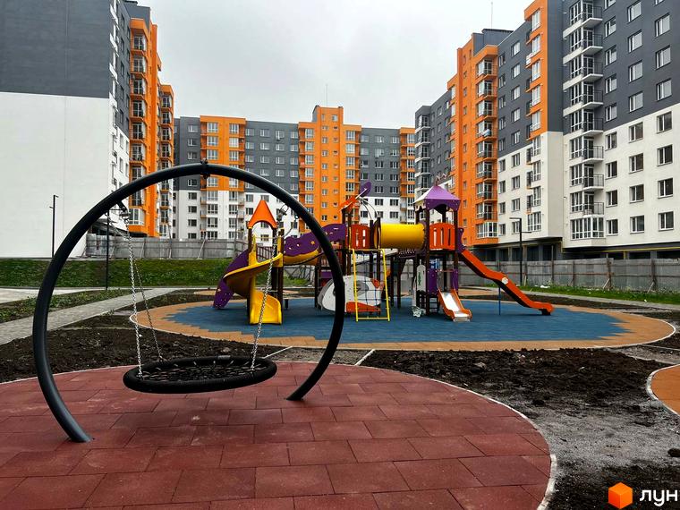 Житловий комплекс Сімейний COMFORT з яскравими фасадами та дитячим майданчиком з гойдалками та гірками. Сучасний житловий комплекс для комфортного життя.