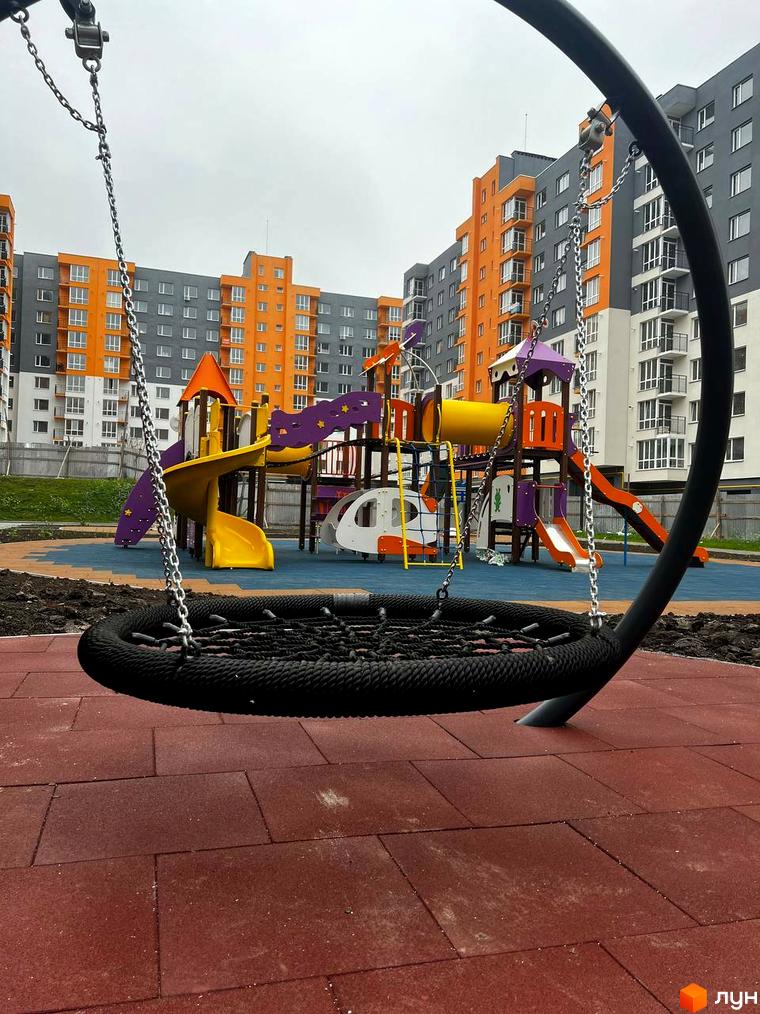 Житловий комплекс Сімейний COMFORT. Дитячий майданчик з гойдалками та гірками на тлі багатоповерхових будинків.