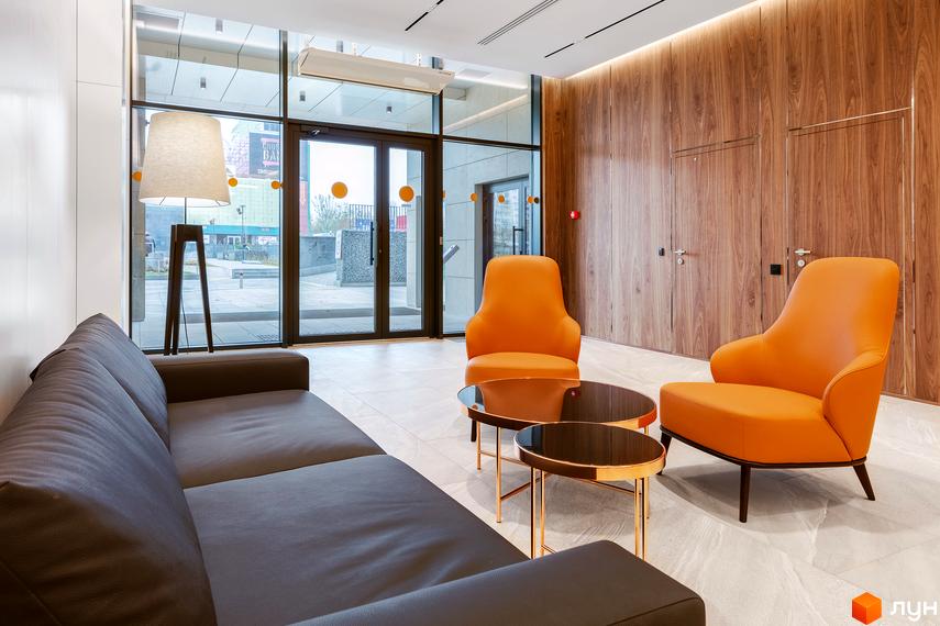 Інтер'єр лобі житлового комплексу Obolon Plaza з диваном, кріслами та журнальними столиками. Великі вікна виходять на міську вулицю.