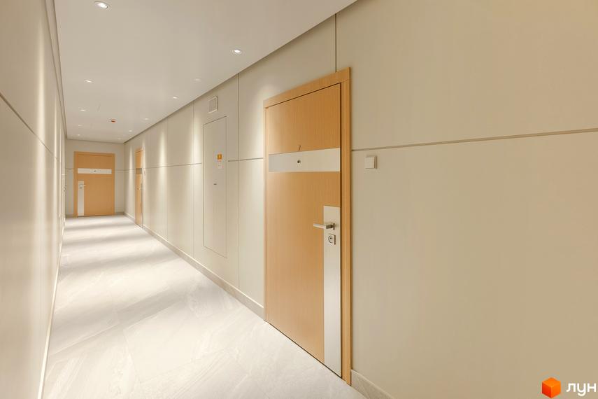 Коридор житлового комплексу Obolon Plaza з дерев'яними дверима та світлою плиткою на підлозі. Сучасний дизайн інтер'єру.
