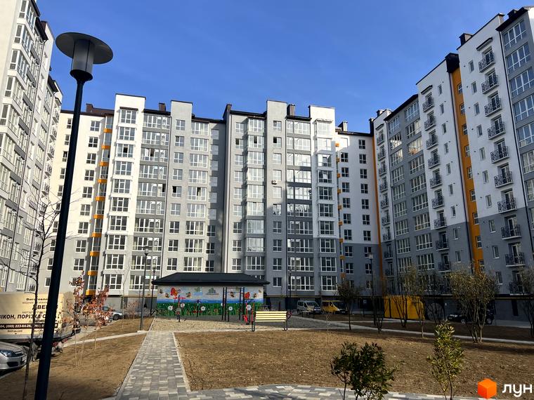 Житловий комплекс Квартал Галицький: багатоповерхові будинки сірого та білого кольору з балконами, внутрішній двір з дитячим майданчиком.