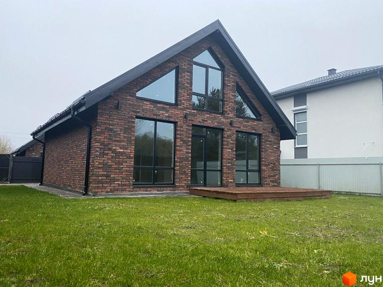 Котеджне містечко КМ Одноповерховий Київ - Віта-Поштова. Будинок з червоної цегли з великими вікнами та дерев'яною терасою на зеленому газоні.