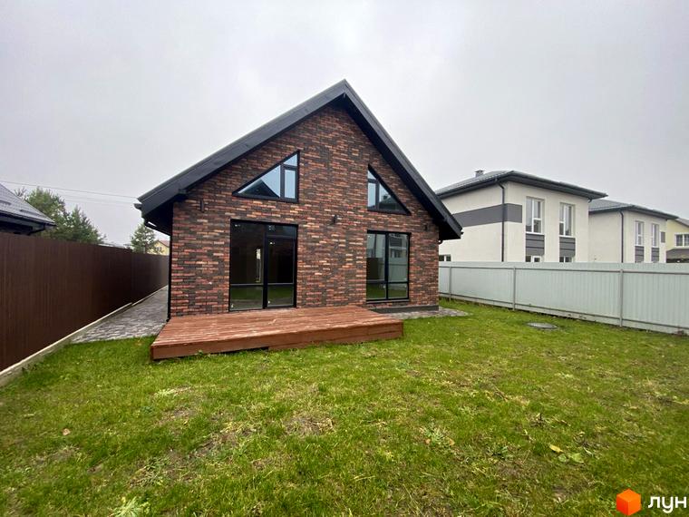Котеджне містечко Одноповерховий Київ - Віта-Поштова. Фасад будинку з червоної цегли, великі вікна, дерев'яна тераса та зелений газон.