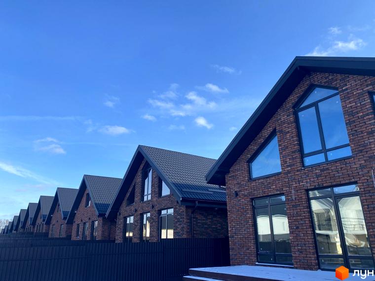 Котеджне містечко КМ Приморська Баварія: цегляні будинки з великими вікнами та темними дахами, розташовані вздовж паркану.