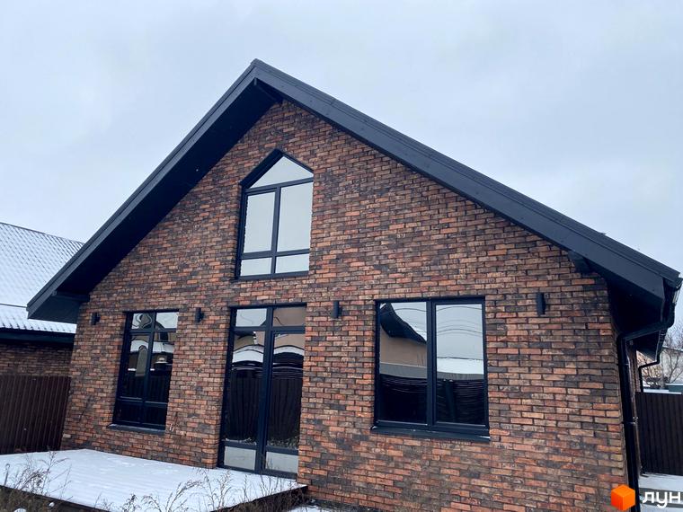 Котеджне містечко КМ Приморська Баварія: цегляний будинок з чорними вікнами та дахом, на тлі сірого неба та снігу.