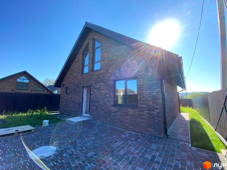 Котеджне містечко КМ Приморська Баварія: двоповерховий будинок з цегляним фасадом та великими вікнами, вимощена бруківкою прибудинкова територія.