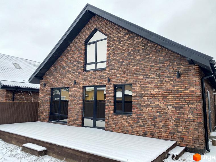 Цегляний будинок з великими вікнами та снігом на терасі. Містечко котеджів Зелена Баварія пропонує комфортне житло.