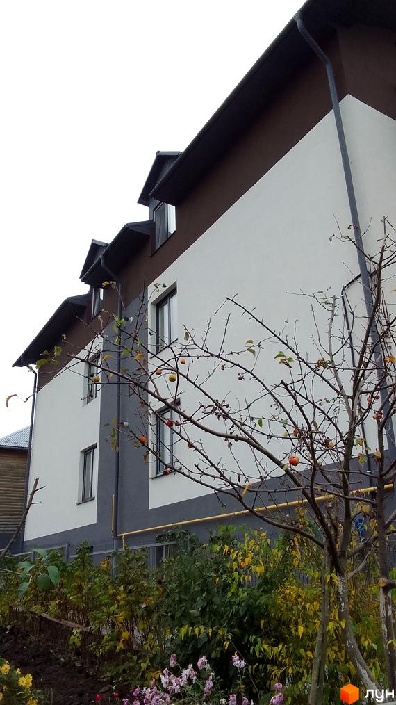 Фасад новобудови на вул. Чернівецька, 17, з прибудинковою територією та деревами восени. Зовнішній вигляд будинку з вікнами та дахом.