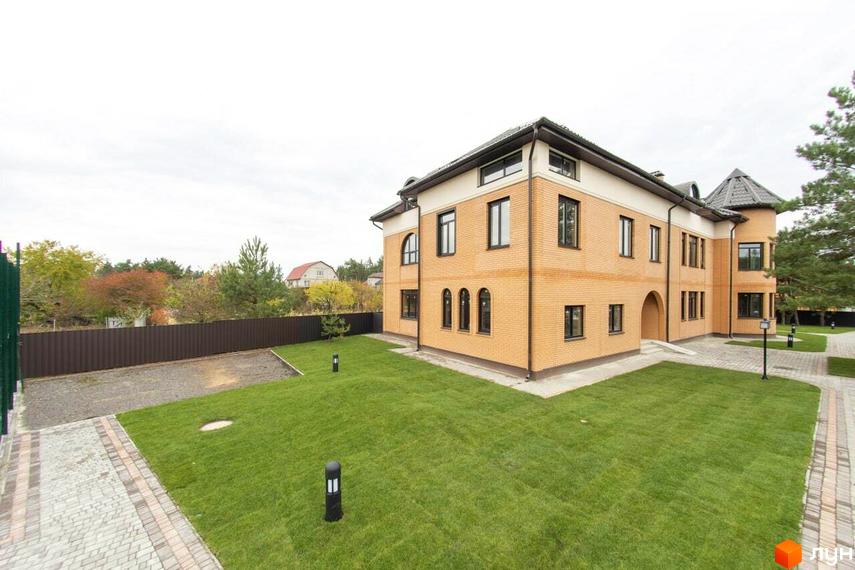 Житловий комплекс Мюнхен: цегляна двоповерхова будівля з темними вікнами та зеленою прибудинковою територією з газоном та доріжками.