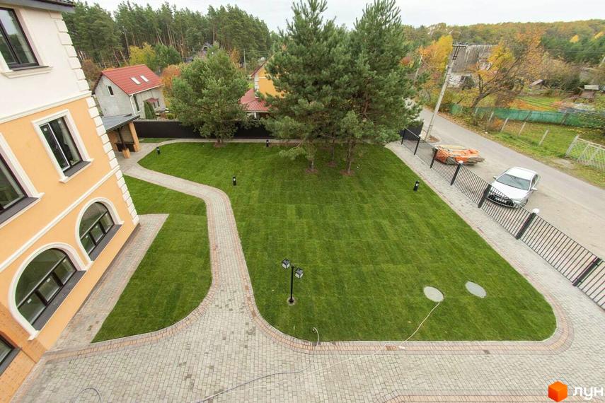 Житловий комплекс Мюнхен: фасад будинку та доглянута прибудинкова територія з газоном і доріжками.