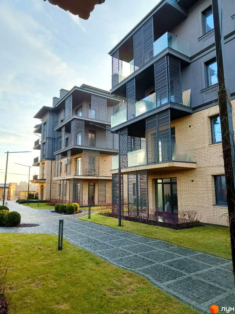 Житловий комплекс Garden Hall: фасади будівель з цегляним оздобленням та скляними балконами. Доглянута прибудинкова територія з доріжками та газонами.