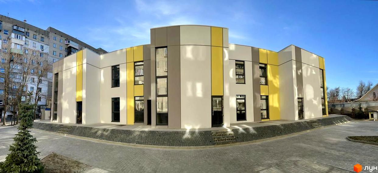 Зовнішній вигляд Клубного будинку ART HOUSE з кольоровими вставками на фасаді. Навколо будівлі облаштована пішохідна зона.