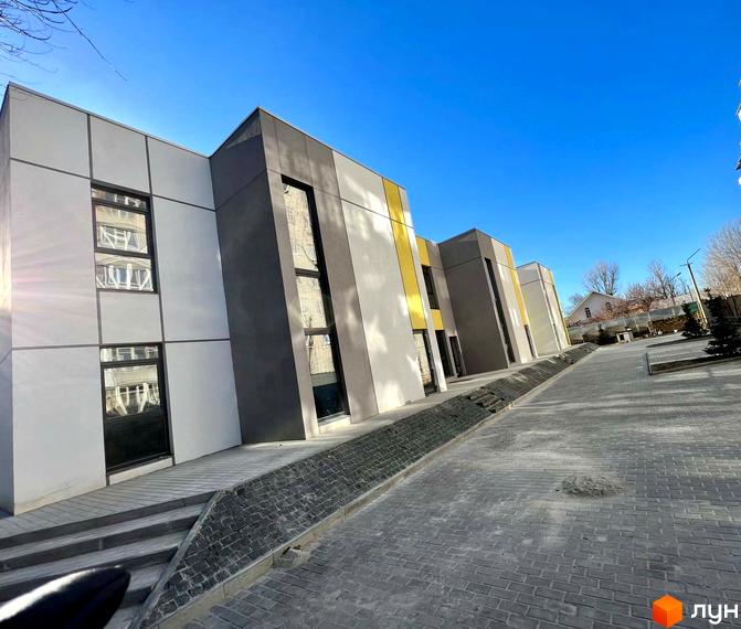 Зовнішній вигляд Клубного будинку ART HOUSE. Фасад будівлі з великими вікнами, перед будинком тротуарна плитка.