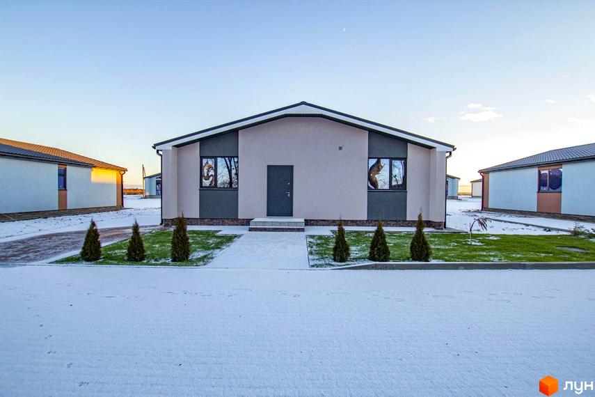 Зовнішній вигляд котеджного містечка КМ Мілленіум взимку. Будинки з сірими та бежевими фасадами, вікна з візерунками, доглянута територія з ялинками та снігом.