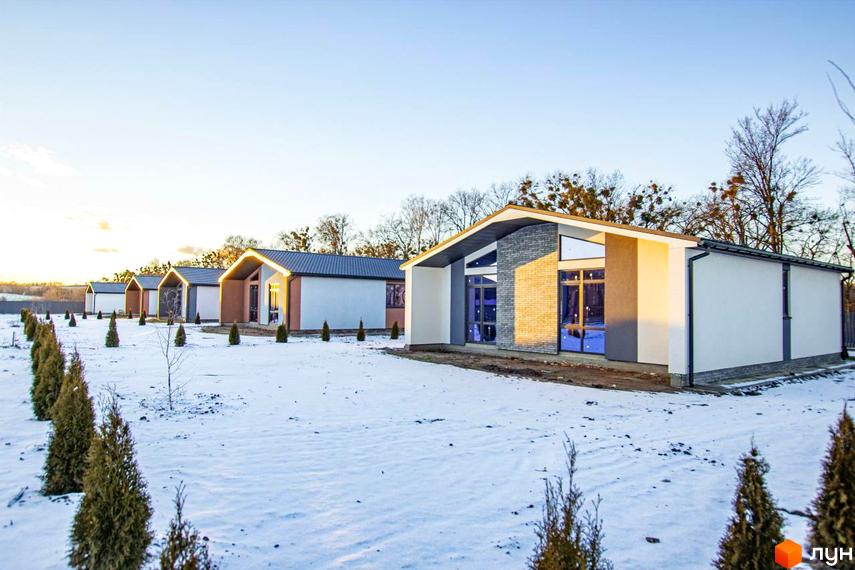 Котеджне містечко КМ Мілленіум. Сучасні одноповерхові будинки з великими вікнами на тлі зимового пейзажу та зелених туй.