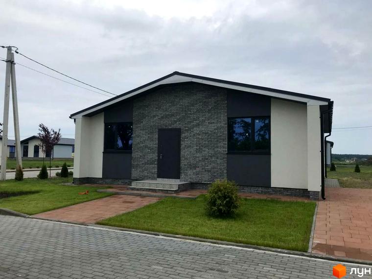 Котеджне містечко КМ Мілленіум: одноповерховий будинок з сірим цегляним фасадом та великими вікнами, доглянута прибудинкова територія з газоном та доріжками.