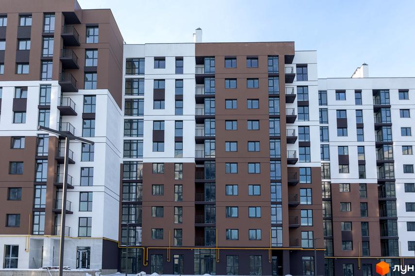 Фасад житлового комплексу Супернова з коричневими та білими секціями, великими вікнами та балконами. Будинок має багатоповерхову структуру з чіткими геометричними формами.