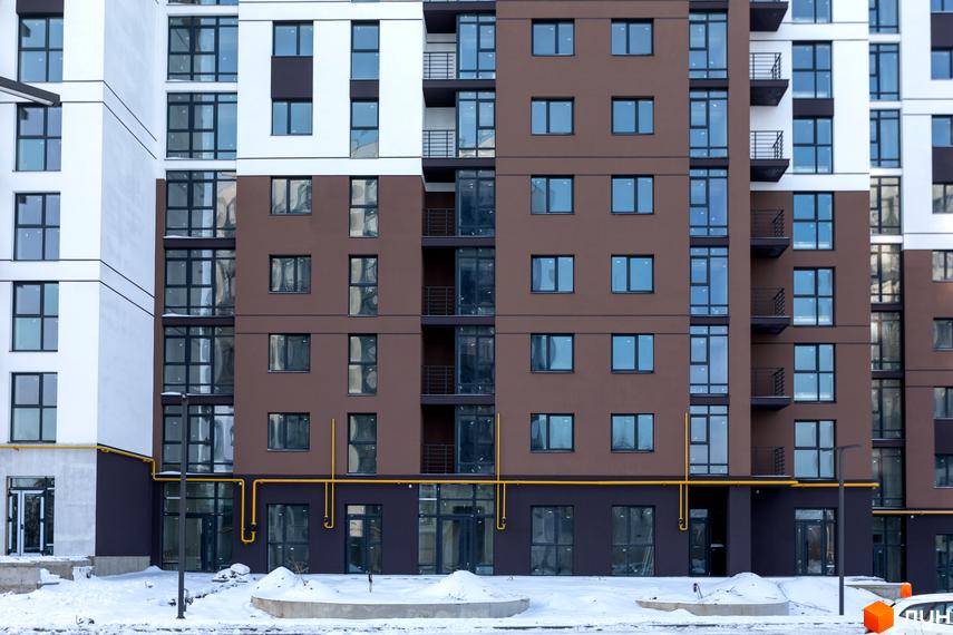 Зовнішній вигляд новобудови ЖК Супернова з коричневими та білими фасадами та великою кількістю вікон. Навколо будинку видно засніжену територію.