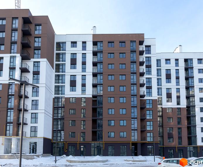Зовнішній вигляд новобудови ЖК Супернова. Багатоповерхові будинки з коричневими та білими фасадами, великою кількістю вікон та балконів. Навколо будівлі видно засніжену територію.
