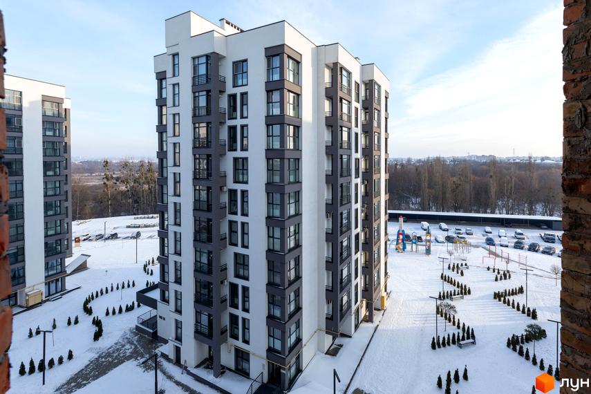 Зовнішній вигляд новобудови ЖК Супернова з сірими та білими фасадами, великою кількістю вікон та балконів. На прибудинковій території розташований дитячий майданчик та парковка.