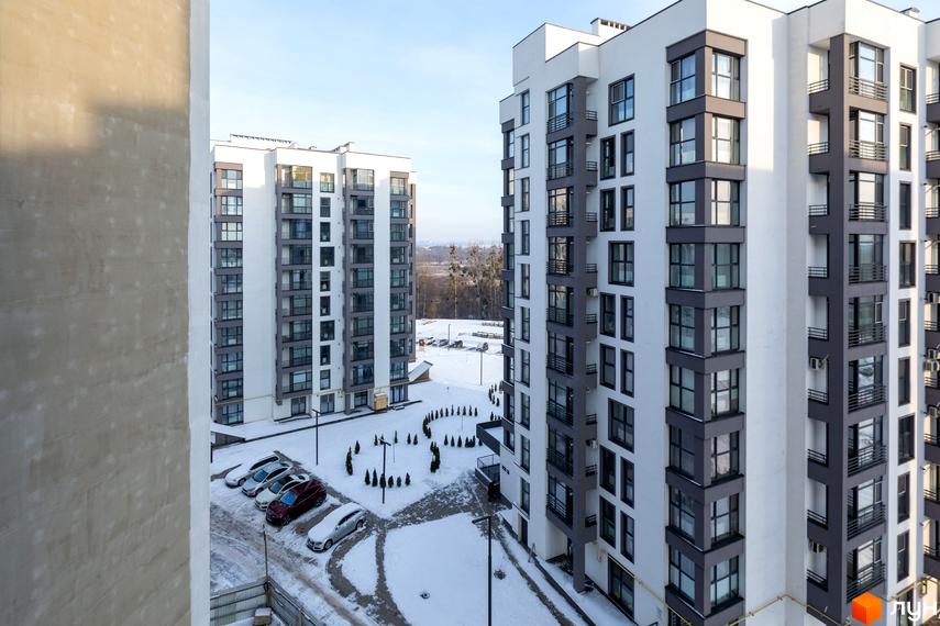 Новобудова ЖК Супернова з біло-сірими фасадами та великою кількістю вікон. Навколо розташовані засніжені дороги та припарковані автомобілі.