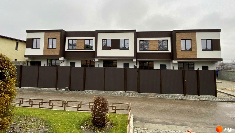 Ряд таунхаусів Living Place з фасадом у коричневих та білих відтінках. Перед будинками розташований коричневий паркан та зелена прибудинкова територія.
