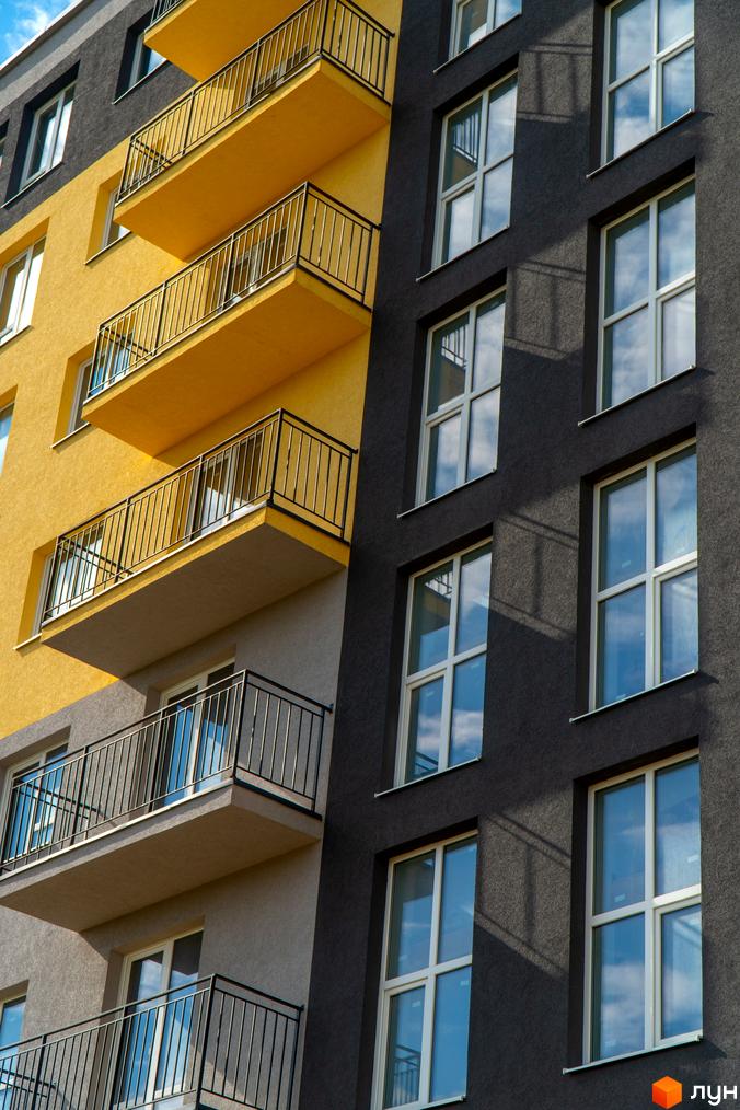 Фасад багатоповерхового будинку у Житловому комплексі Зелені Пагорби з балконами та великими вікнами.