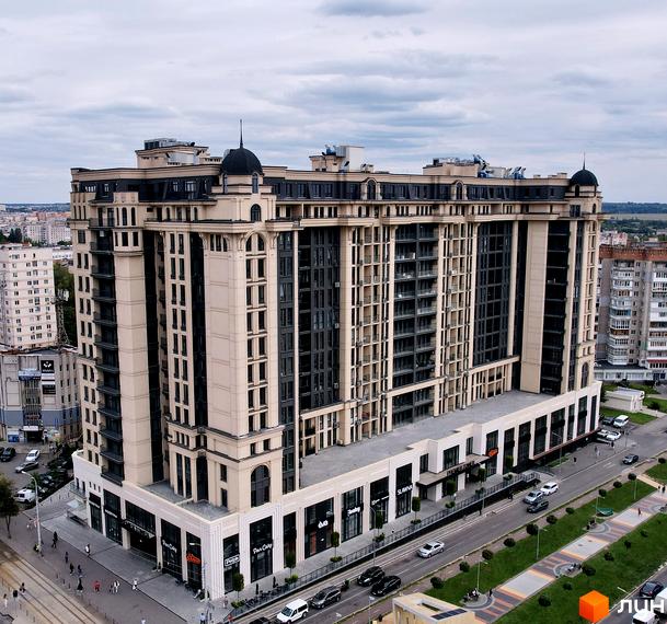Висотна будівля Житловий комплекс Premier Tower з великими вікнами та світлим фасадом. На прибудинковій території розташовані зелені насадження та дорога з автомобілями.