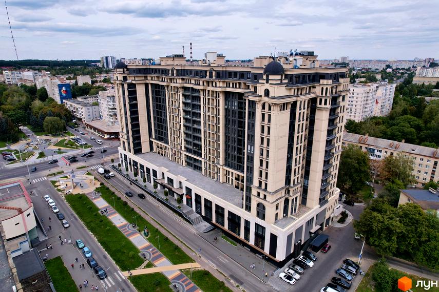 Житловий комплекс Premier Tower: багатоповерховий будинок зі світлим фасадом та темними вікнами. Прибудинкова територія з дорогами, парковками та зеленими зонами.