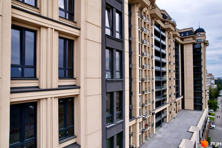 Житловий комплекс Premier Tower з бежевим фасадом, темними вікнами та балконами. Поруч проїжджа частина та пішохідна зона.