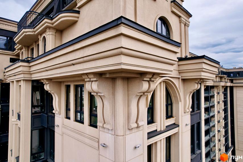 Житловий комплекс Premier Tower: деталі фасаду багатоповерхового будинку з бежевою обробкою, декоративними кронштейнами та арковими вікнами.
