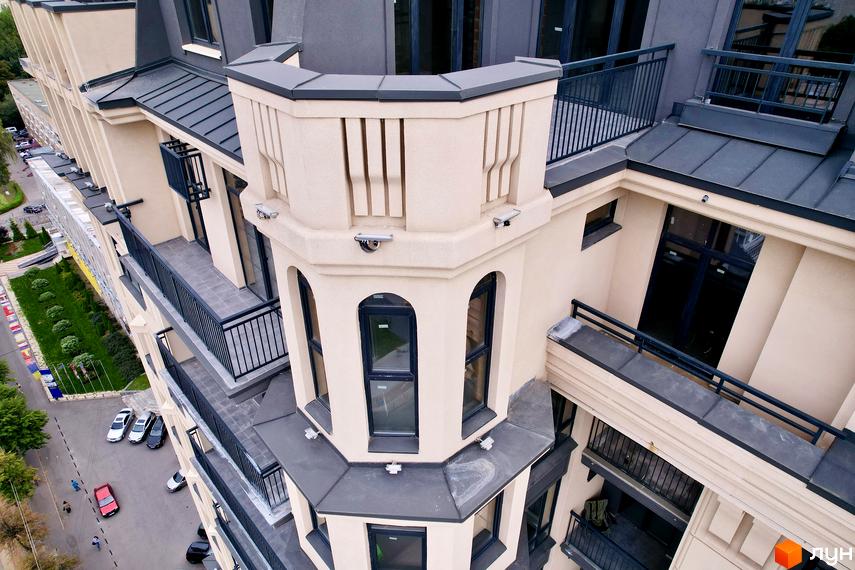 Зображення Житлового комплексу Premier Tower з акцентом на фасад, балкони та кутову вежу. Видно прилеглу територію з дорогою та зеленими насадженнями.