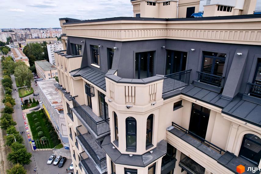 Вид зверху на Житловий комплекс Premier Tower з бежевим фасадом, темними дахами та балконами. Поруч вулиця з деревами та міська забудова.