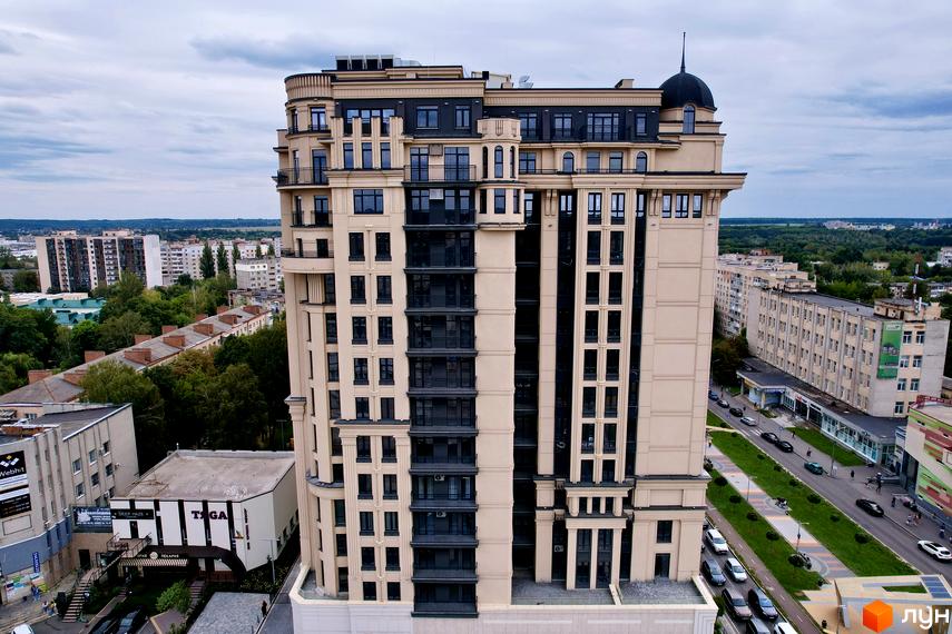 Житловий комплекс Premier Tower: висотна будівля з бежевим фасадом, темними вікнами, балконами та куполом на даху. Поруч вулиця з транспортом.