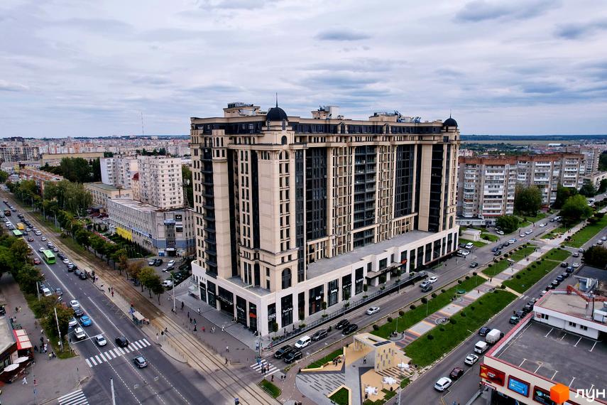 Житловий комплекс Premier Tower. Висотна будівля з великою кількістю вікон та балконів. Навколо будинку розташовані дороги, тротуари та зелені насадження.