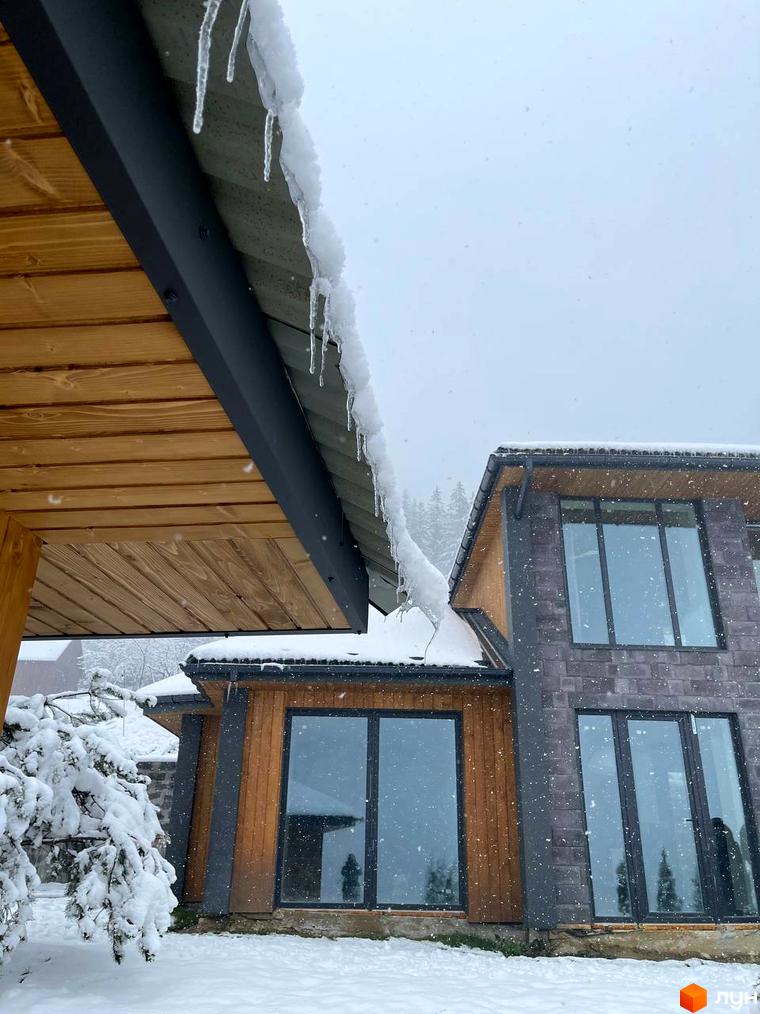 Котеджне містечко КМ Агат Резорт & SPA взимку, з льодом на даху та засніженими деревами.